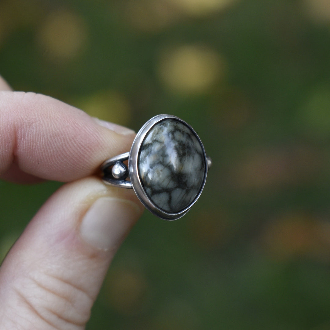 Silver ring with a stone held by a hand against a blurred natural background