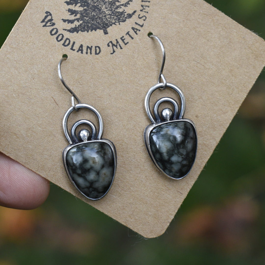 Pair of silver and stone earrings on a 'Woodland Metalsmith' branded card.