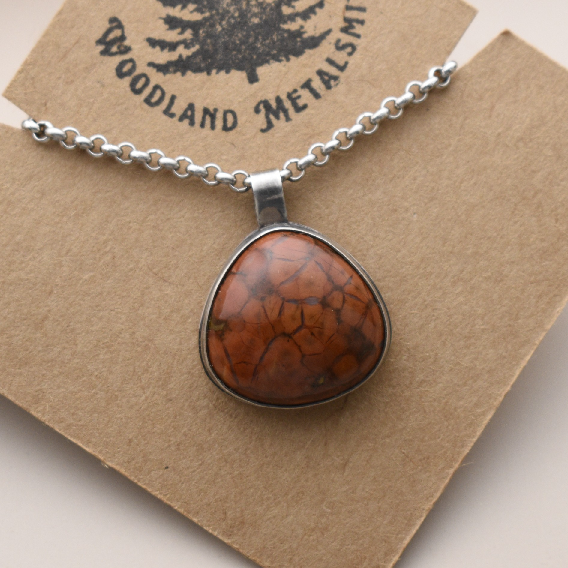 A silver necklace with an orange Jasper stone.