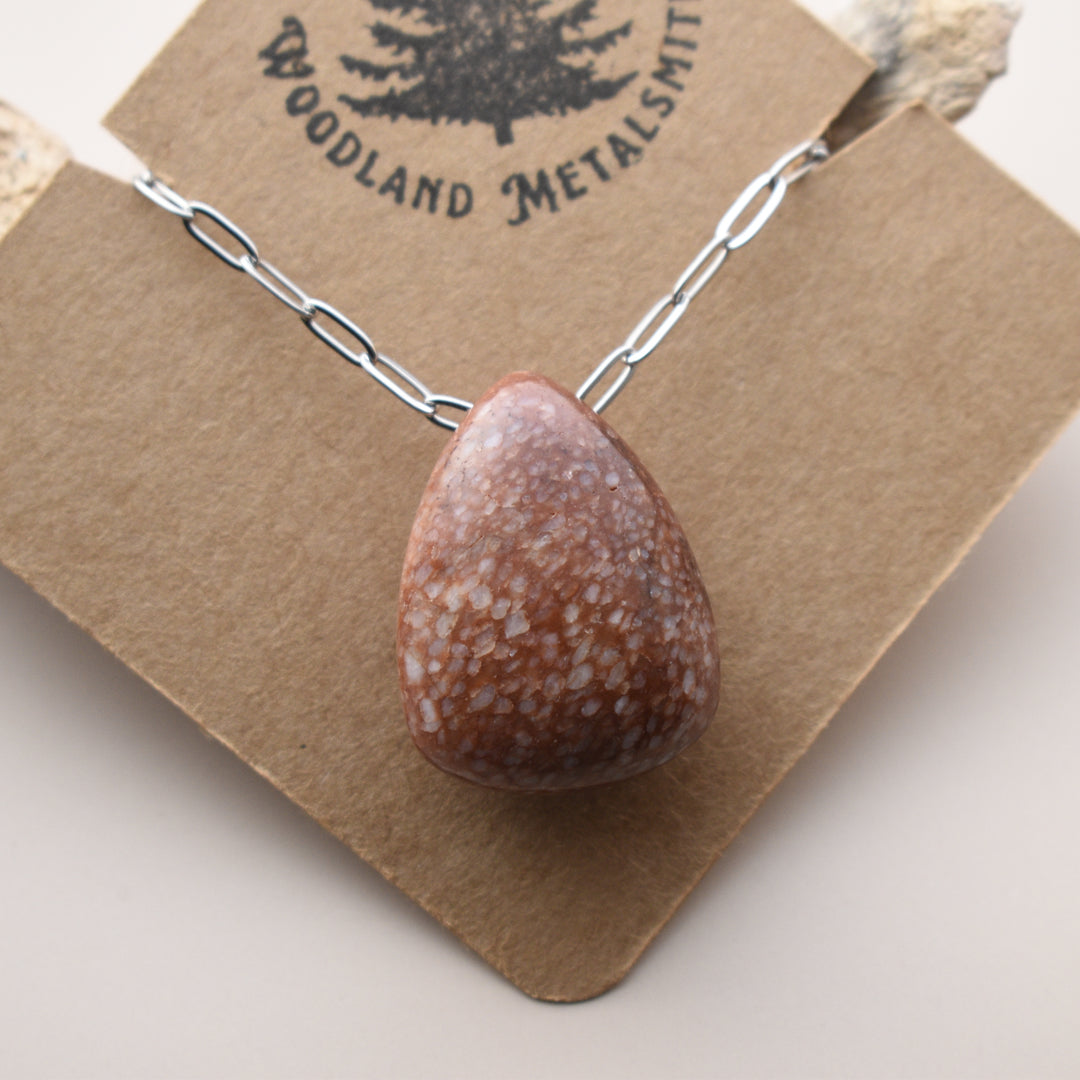 Necklace with a teardrop-shaped stone pendant on a 'Woodland Metalsmith' branded card.