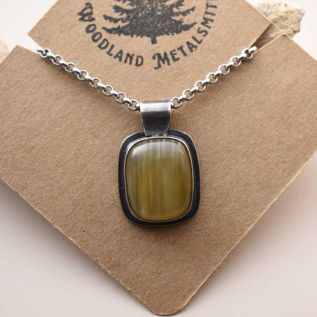 Necklace with a yellow stone pendant on a 'Woodland Metalsmith' branded card.