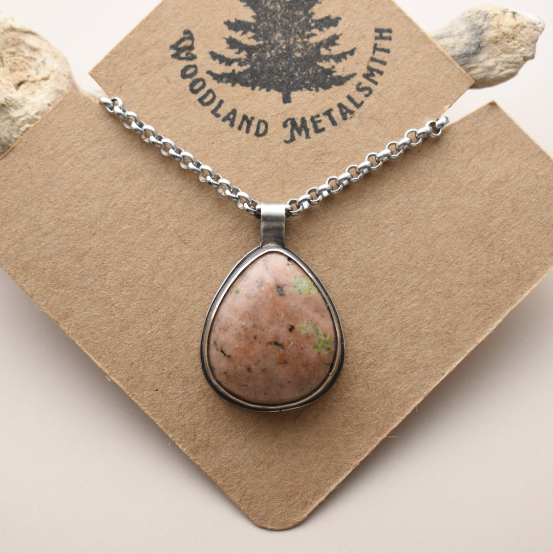 Calcite necklace with a teardrop-shaped stone pendant on a 'Woodland Metalsmith' card.