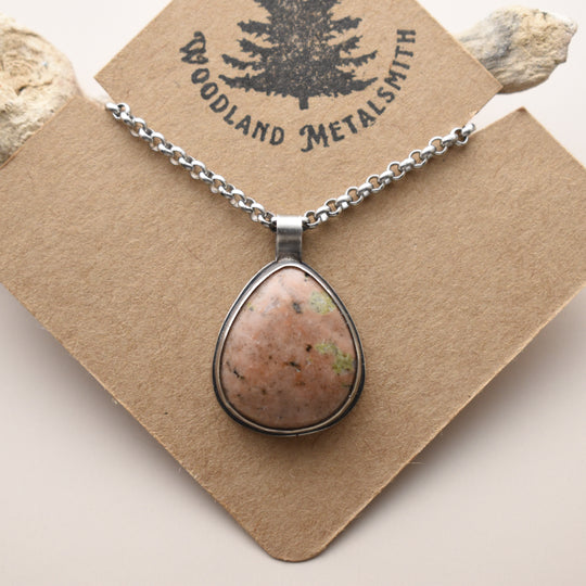 Calcite necklace with a teardrop-shaped stone pendant on a 'Woodland Metalsmith' card.
