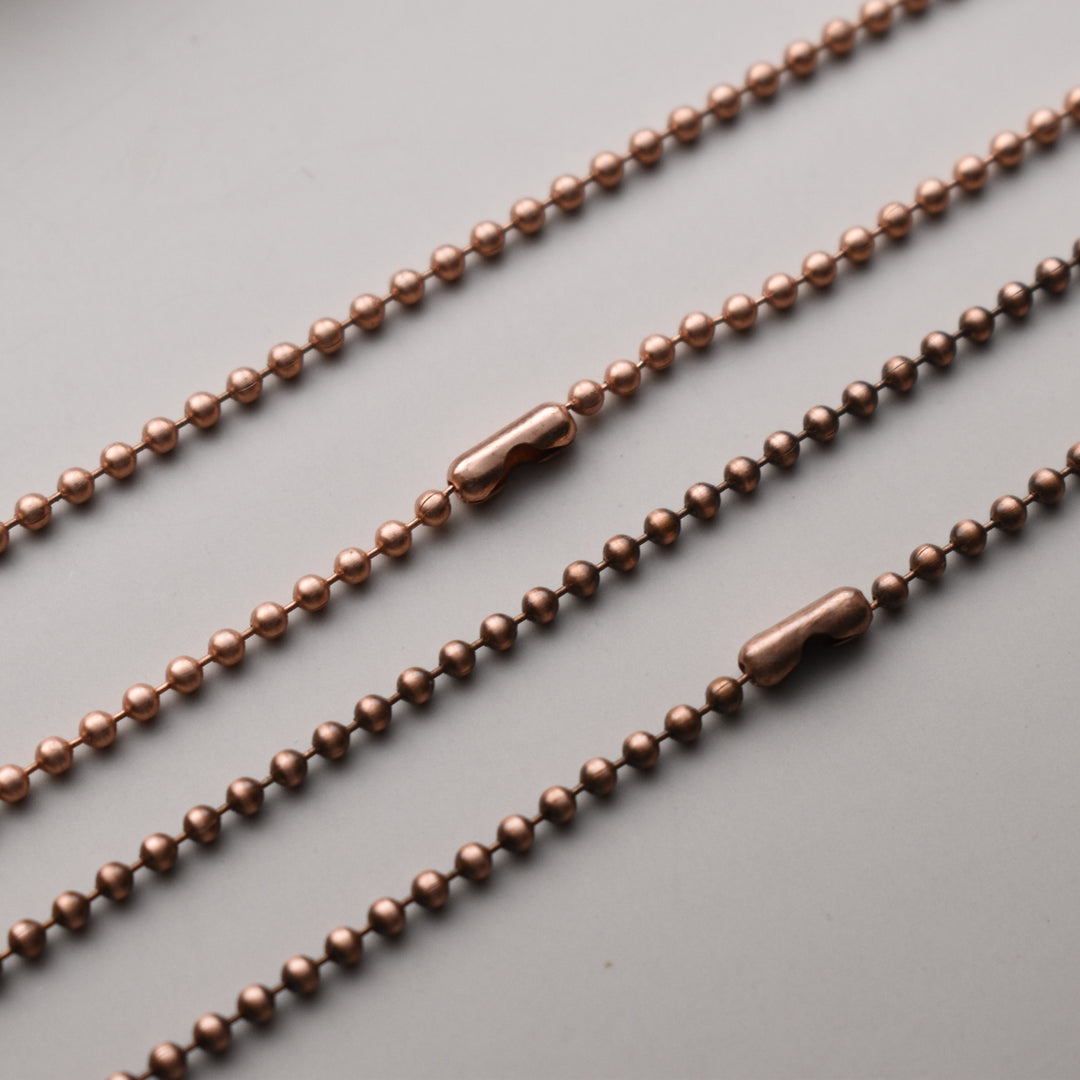 Three copper-colored beaded chains on a gray background