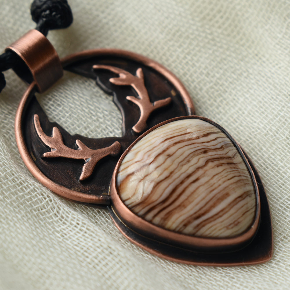 metalsmith pendant handcrafted with deer antlers and petrified wood