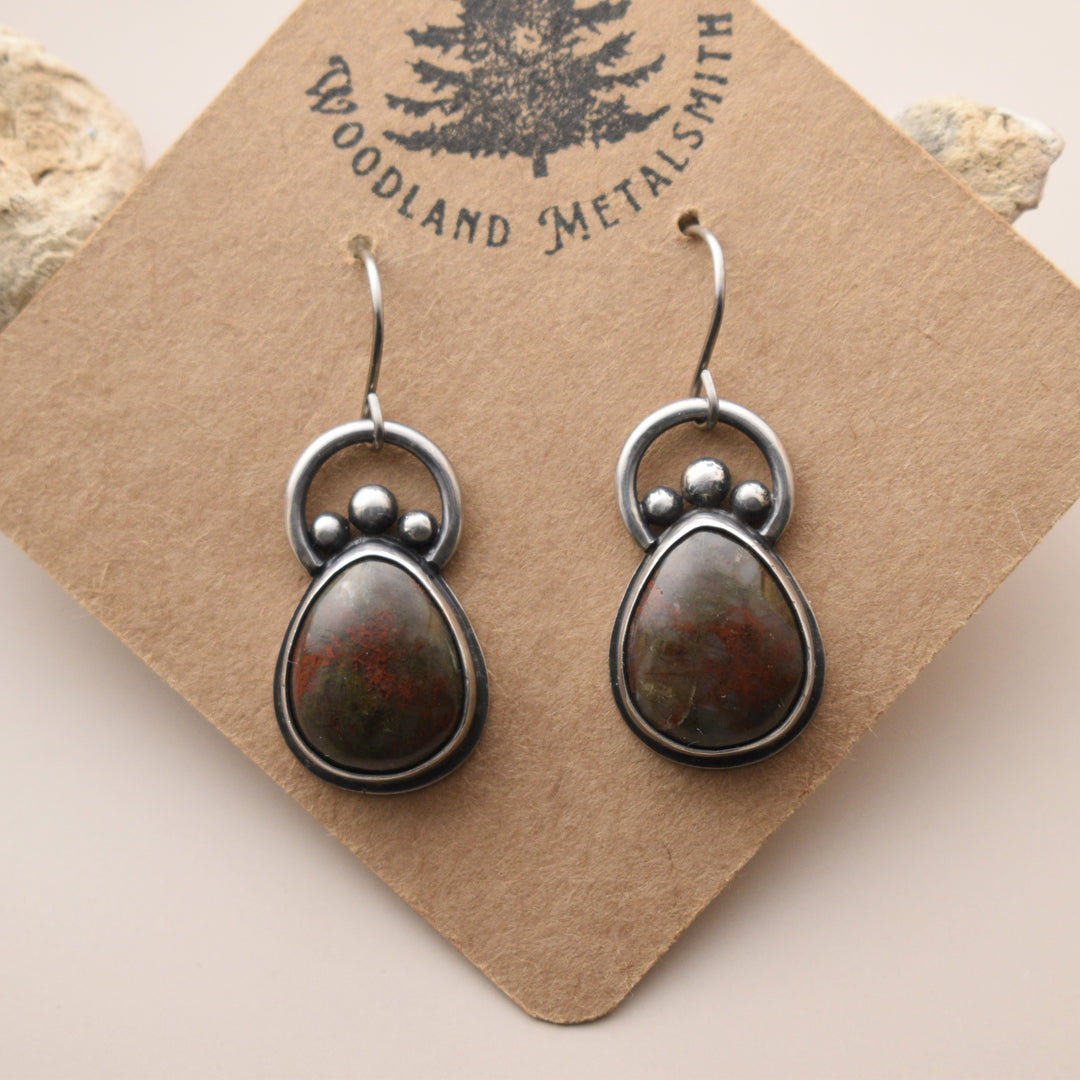 Pair of silver and stone earrings on a 'Woodland Metalsmith' branded card.