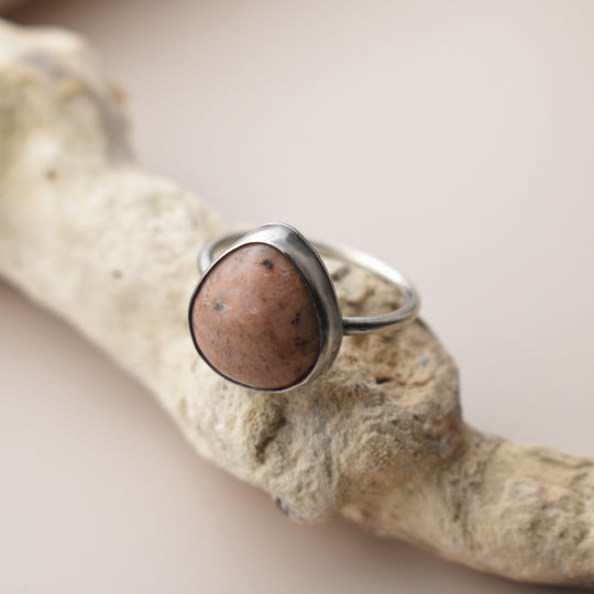 Silver ring with a calcite stone on a textured beige surface