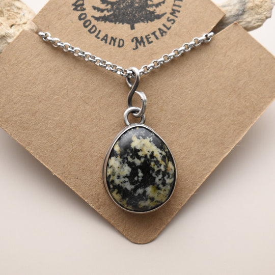 Necklace with a stone pendant on a brown card, featuring 'Woodland Metalsmith' branding.