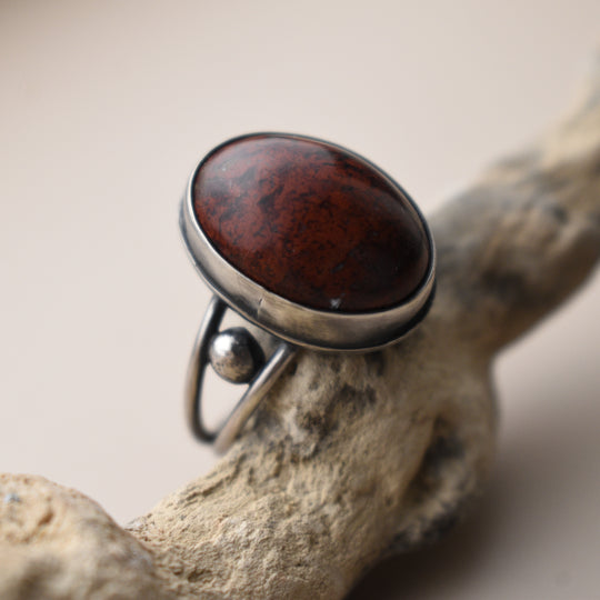 Silver ring with a red stone on a wooden surface