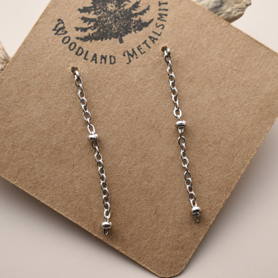 Pair of silver chain earrings on a Woodland Metalsmith branded card.