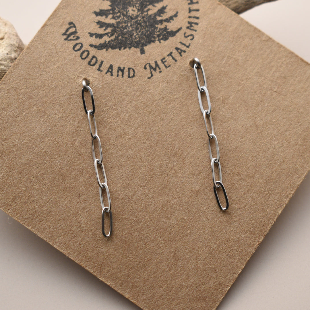 Silver chain earrings on a 'Woodland Metalsmith' branded card.