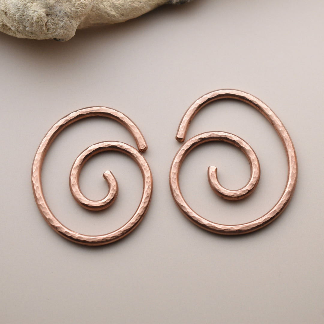 Pair of copper spiral earrings on a neutral background