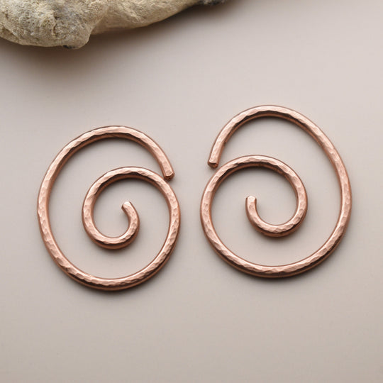 Pair of copper spiral earrings on a neutral background