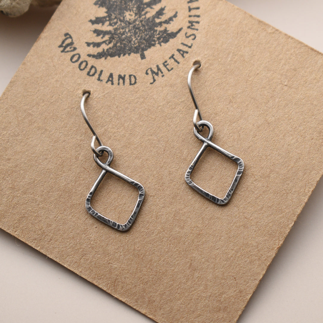 Silver square earrings on a 'Woodland Metalsmith' branded card.