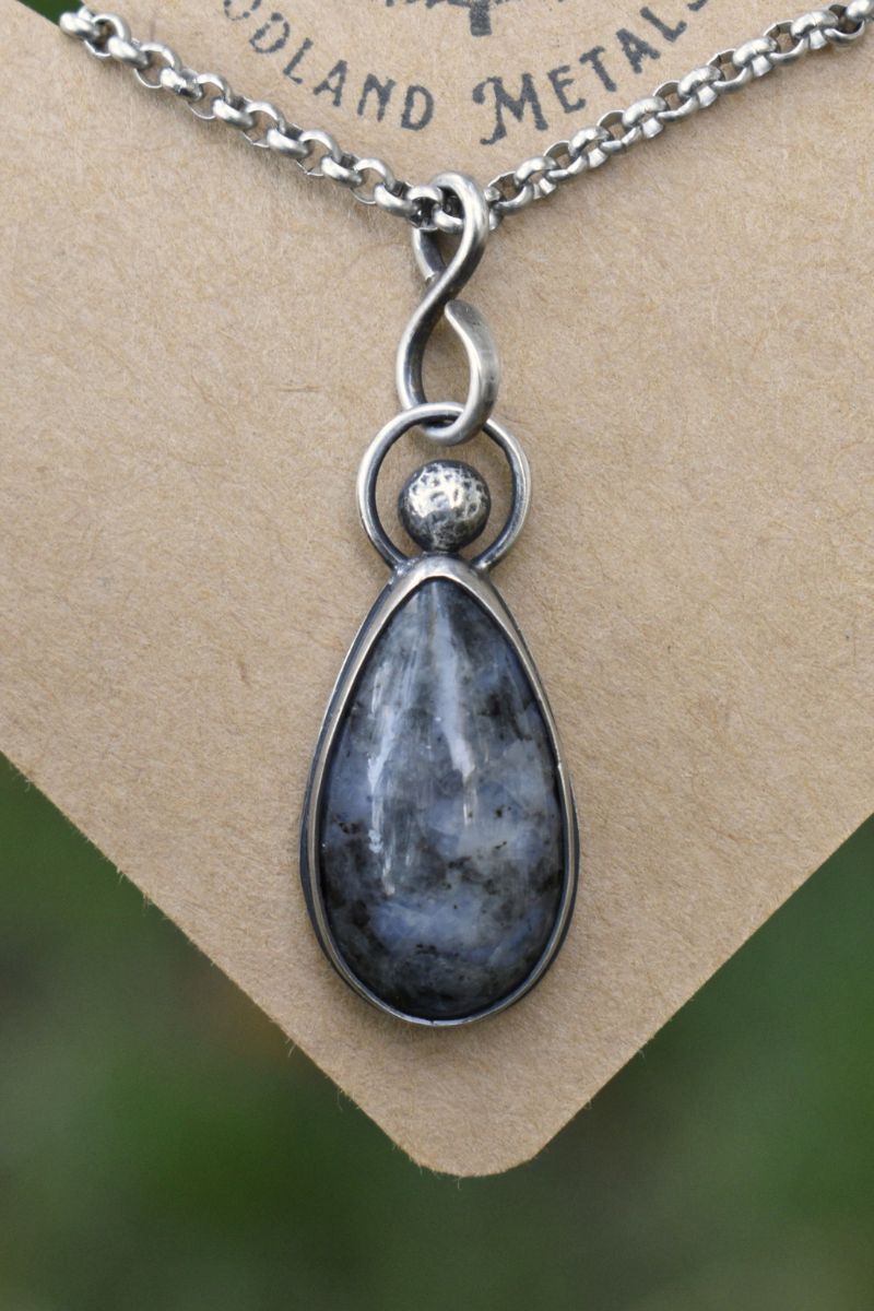 Silver pendant with a teardrop-shaped Diorite stone on a chain, displayed on a brown card.