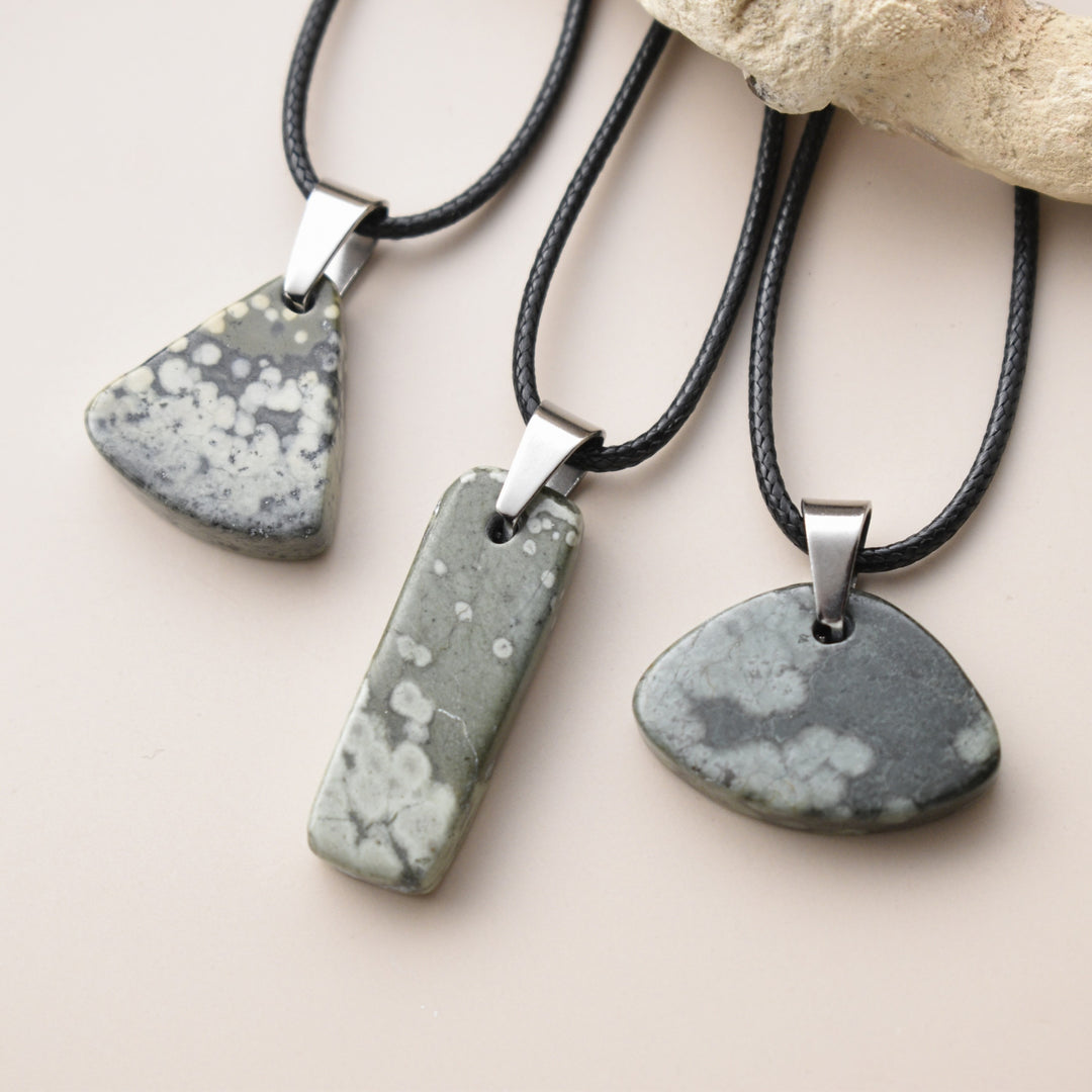 Three stone pendants on leather cords with a neutral background