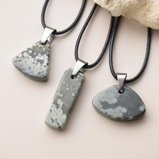 Three stone pendants on leather cords with a neutral background