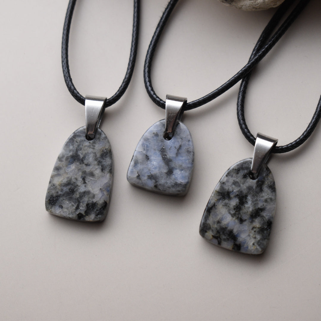 Three stone pendants on black cords with silver clasps on a light background