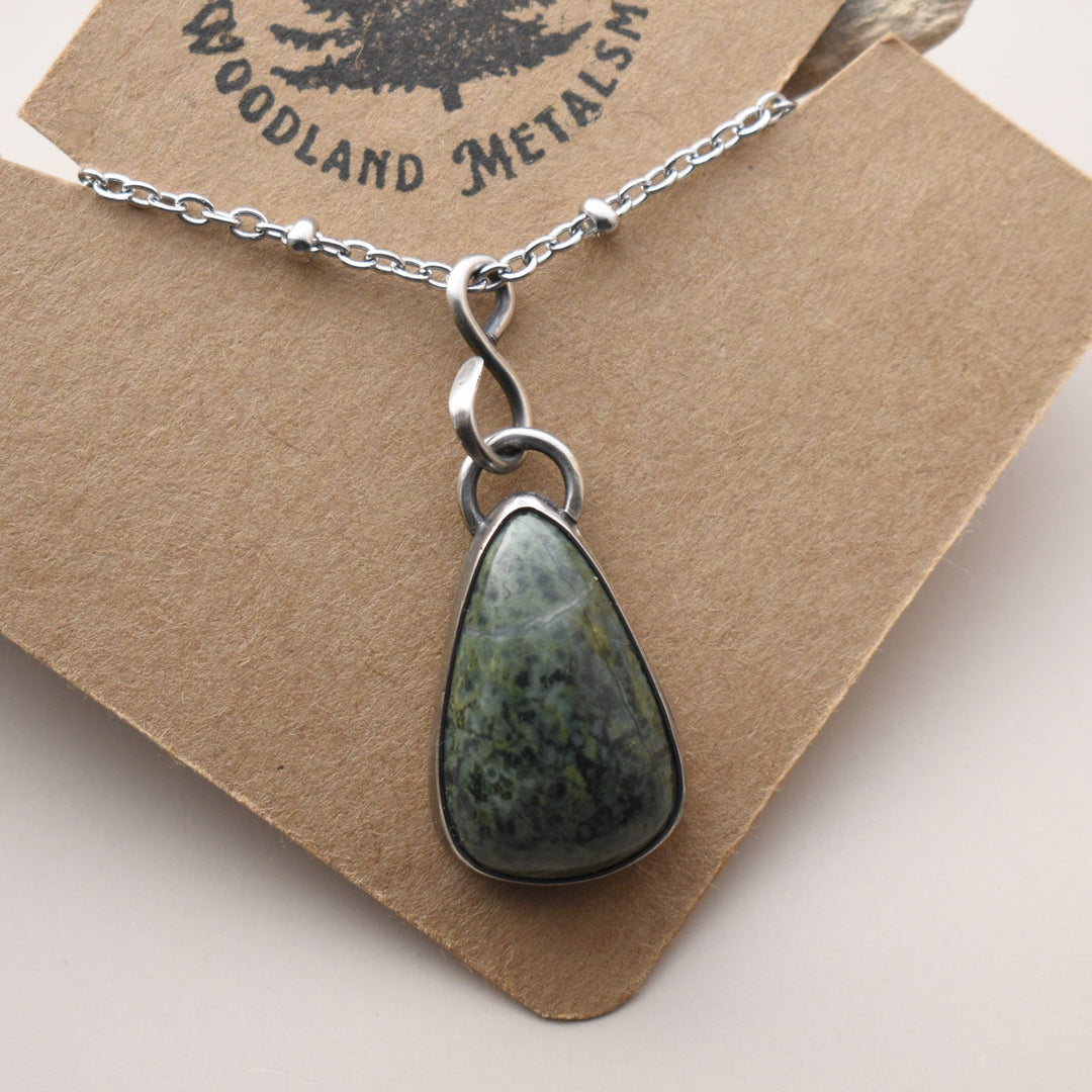 Necklace with a green stone pendant against a wooden background