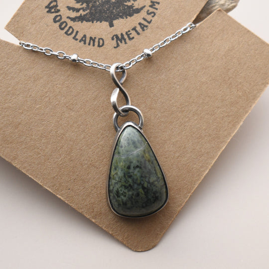 Necklace with a green stone pendant against a wooden background