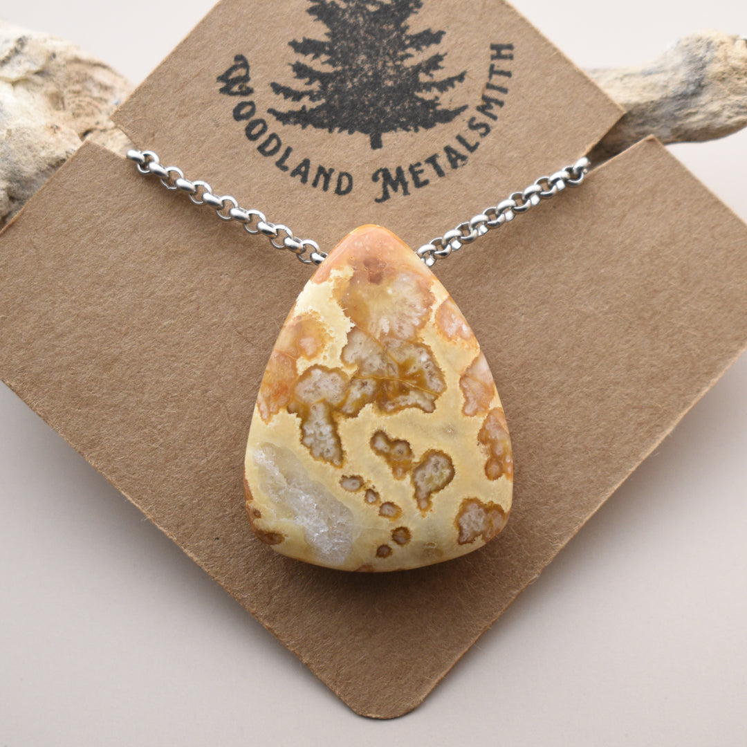 Necklace with a teardrop-shaped stone pendant on a 'Woodland Metalsmith' card.