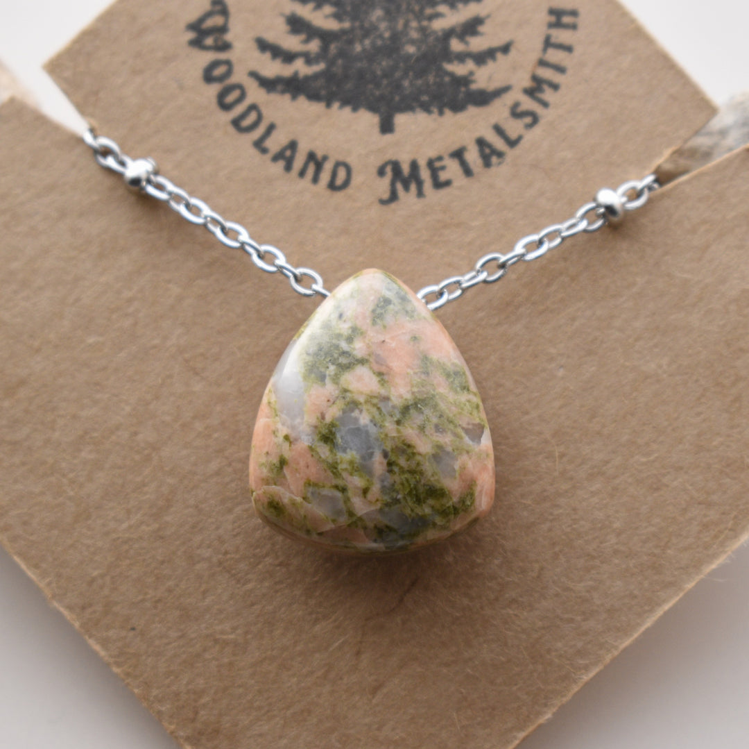 Necklace with a teardrop-shaped stone pendant on a Woodland Metalsmith branded card.